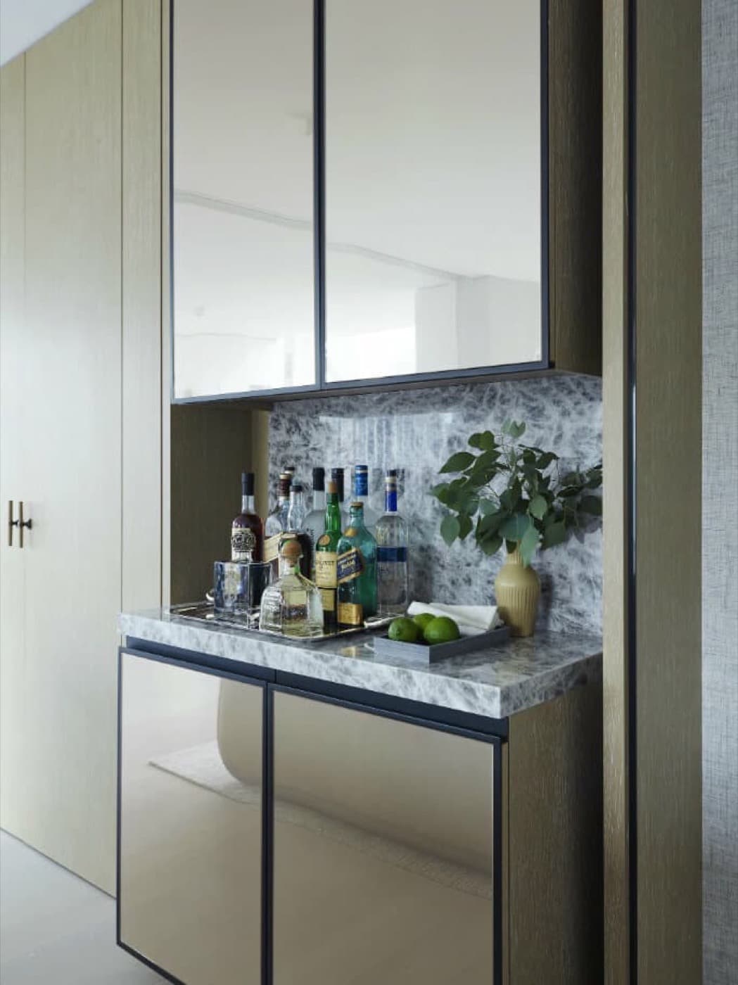 Built-in home bar with mirrored cabinets, grey veined stone countertop, and timber surround