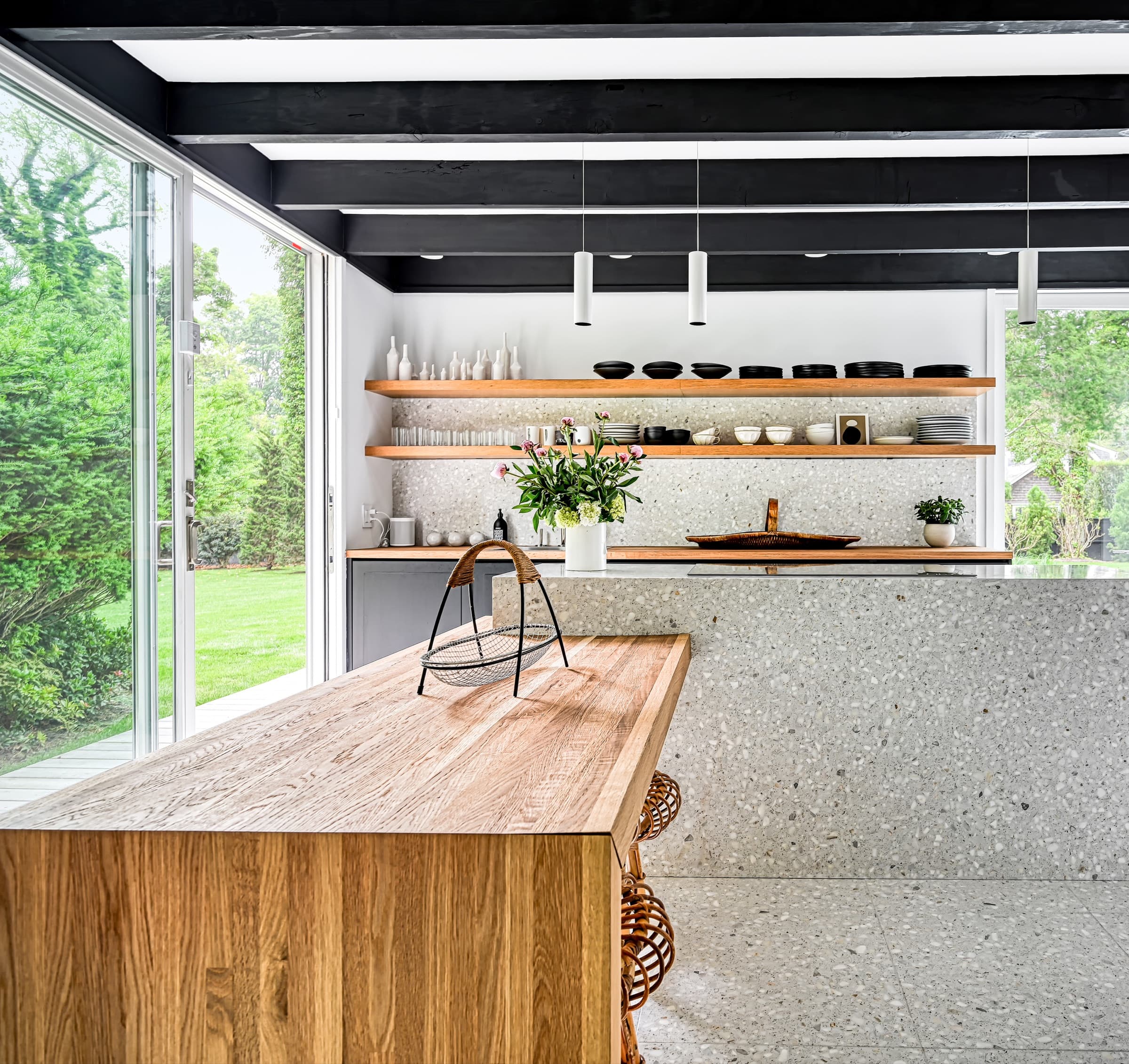 Modern kitchen featuring a timber island counter, speckled stone surfaces, and open floating shelves