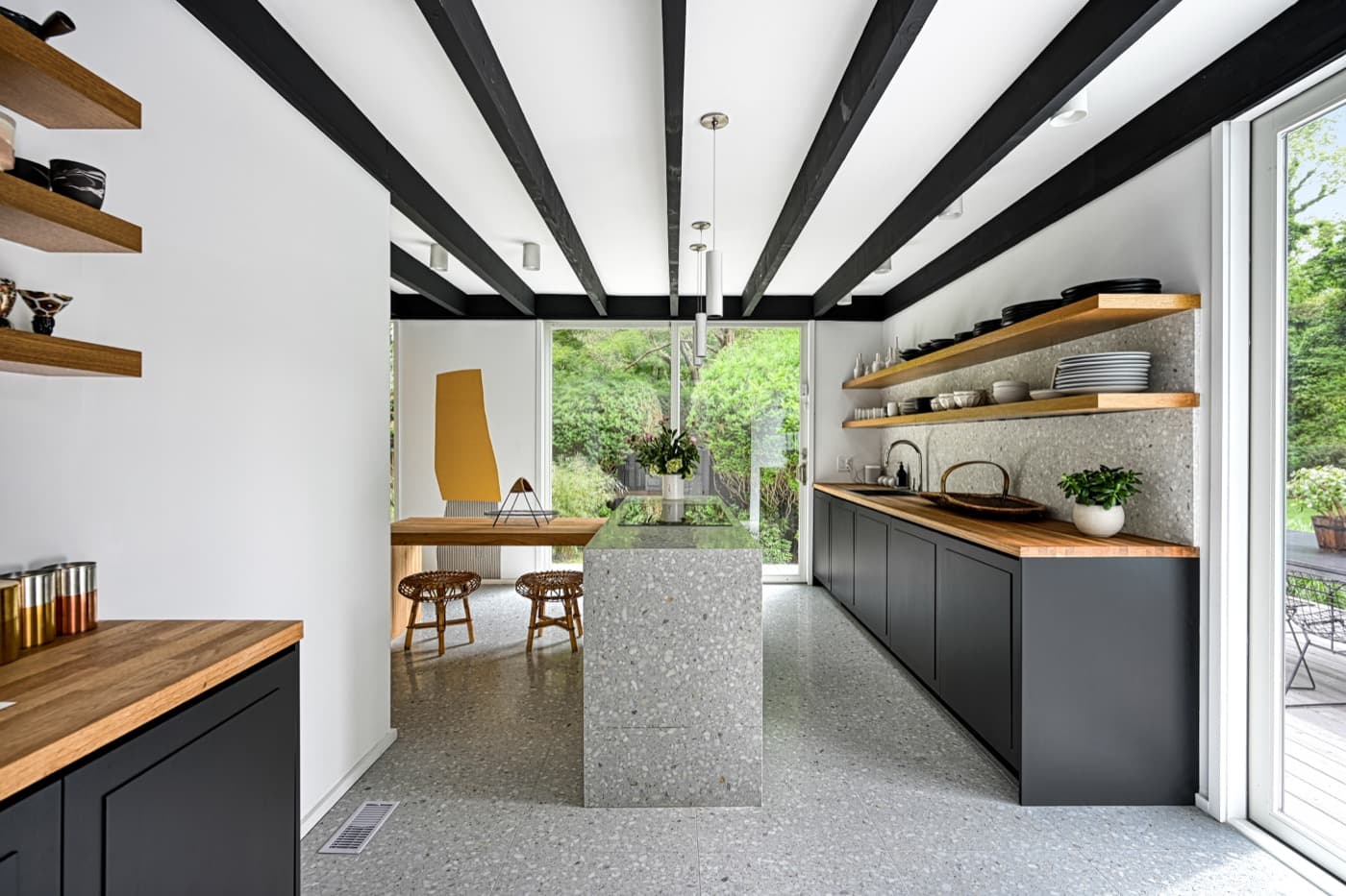 Modern kitchen featuring a terrazzo island, dark lower cabinetry, and floating timber shelves