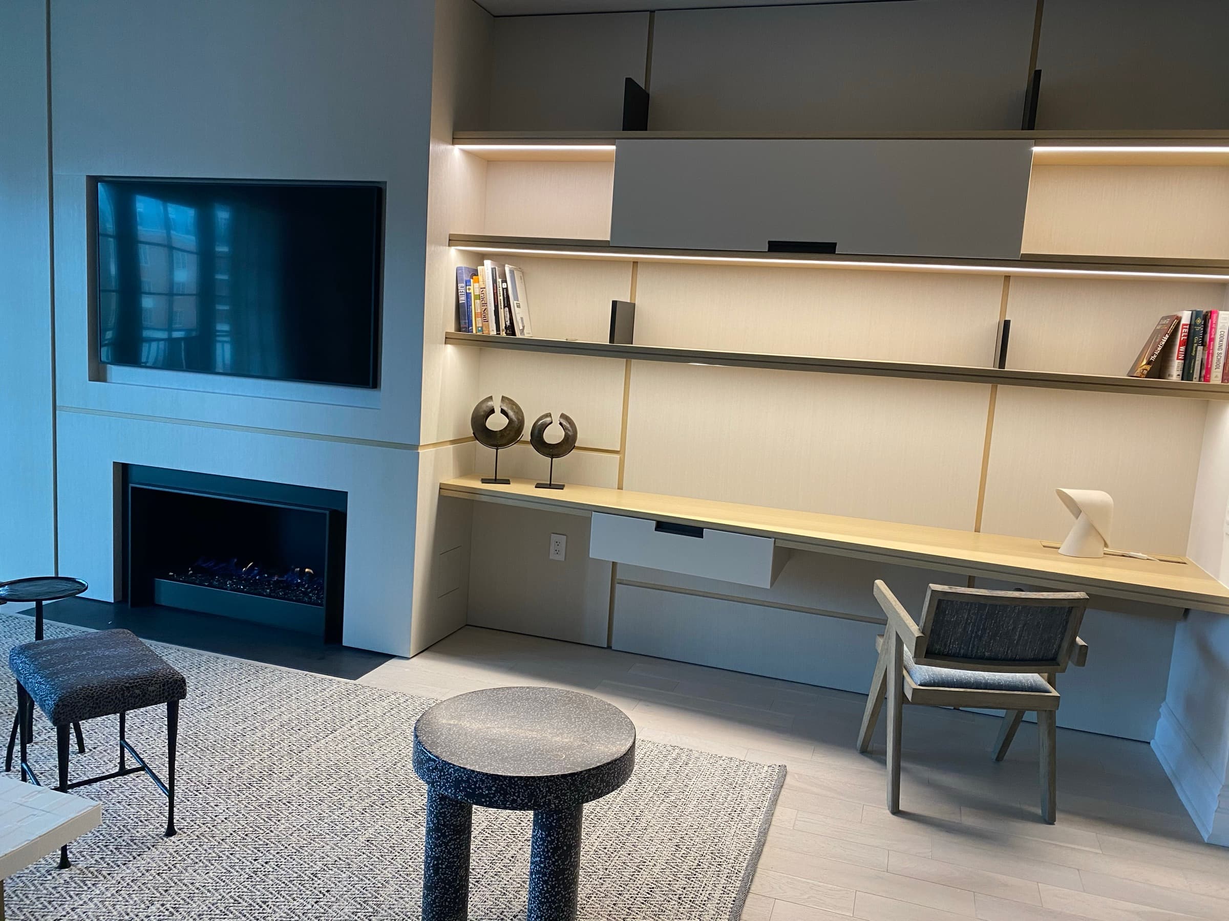 Living room featuring custom illuminated desk shelving and panelling beside an integrated fireplace