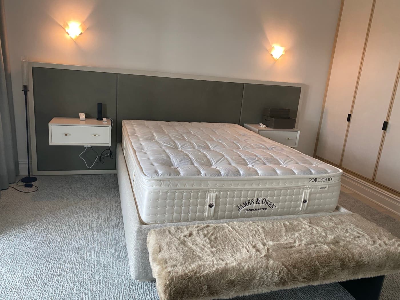 Bedroom featuring upholstered headboard panelling with integrated floating nightstands and built-in wardrobes