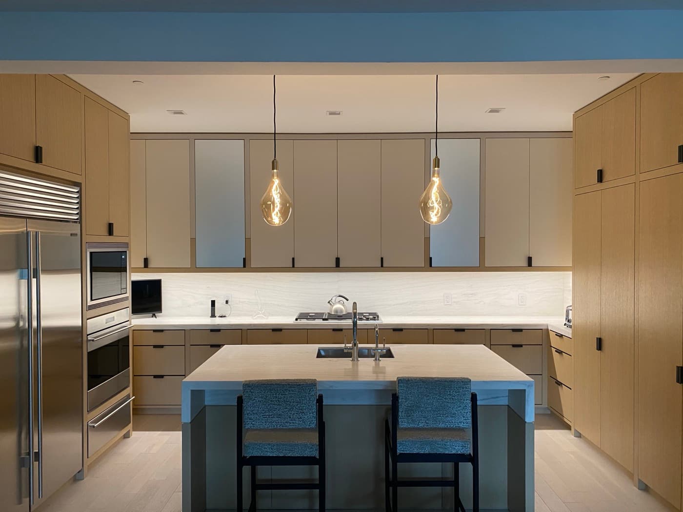 Kitchen with custom light-toned timber cabinetry, stone countertops, and a central island