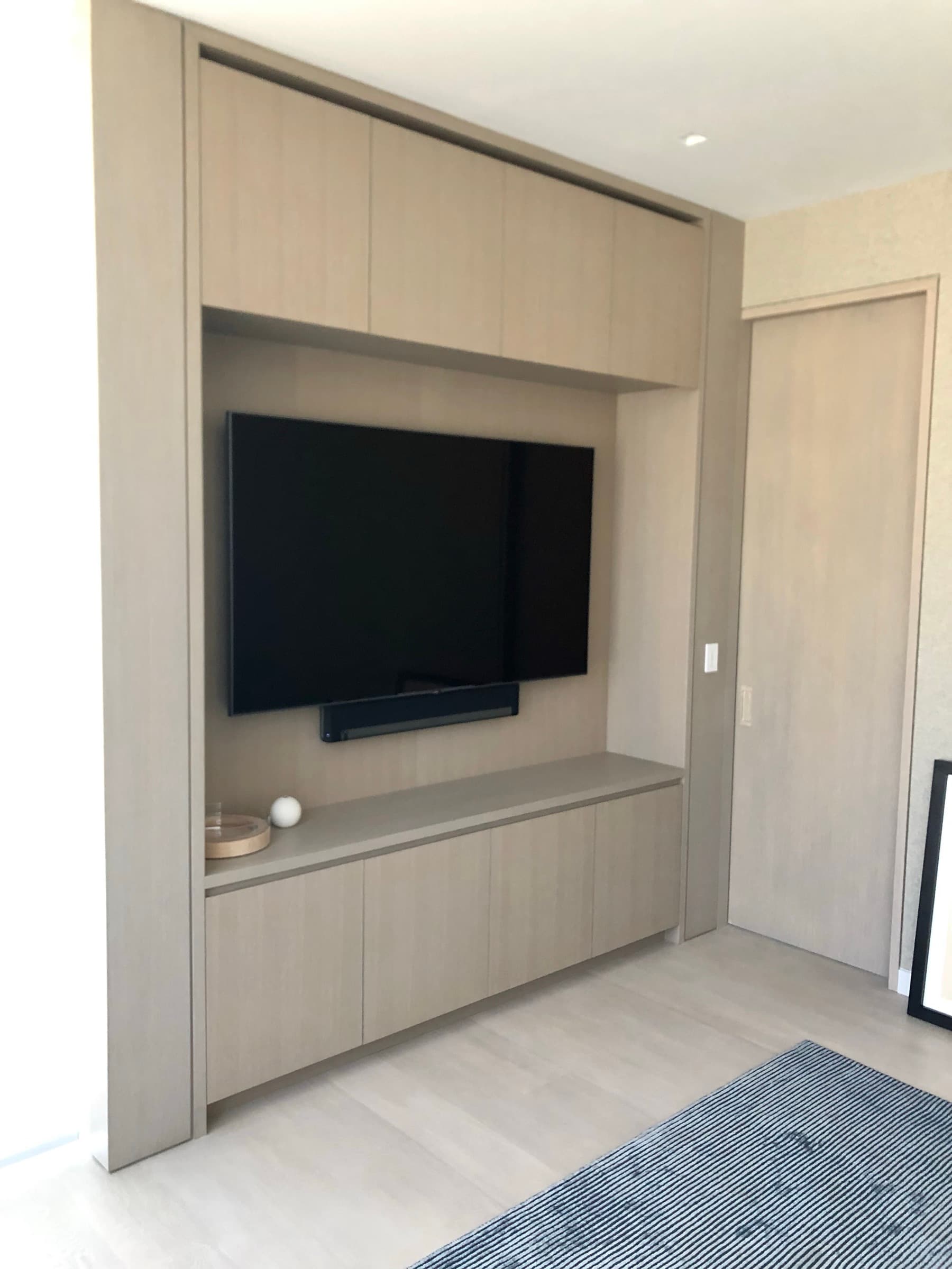 Living room with pale timber built-in media cabinetry framing a recessed television