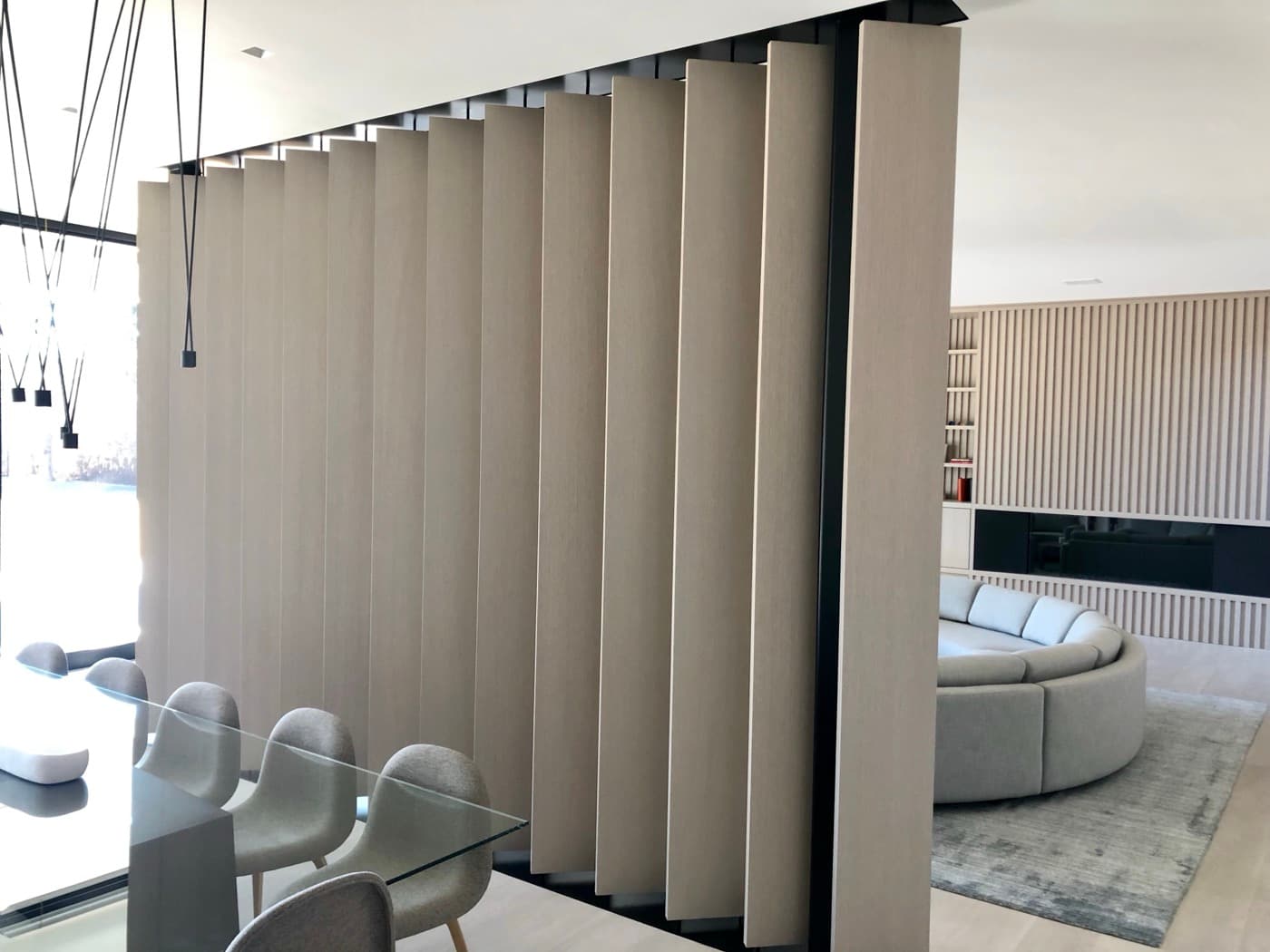 Dining and living room featuring a pivoting pale timber panel partition and slatted feature wall