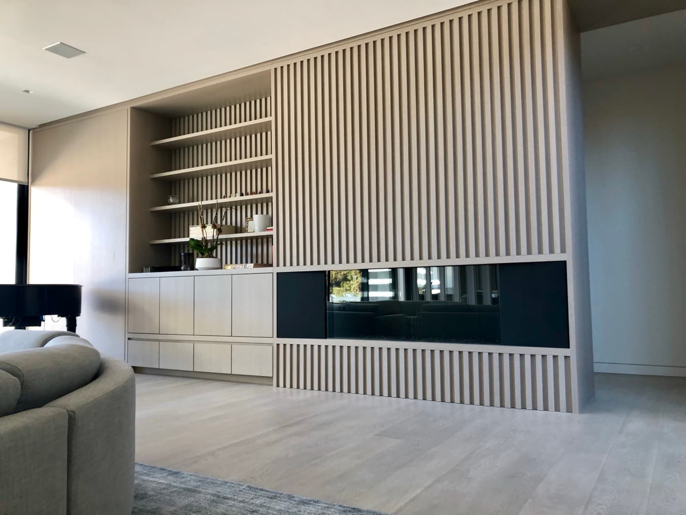 Living room featuring slatted timber wall panelling with integrated linear fireplace and built-in shelving
