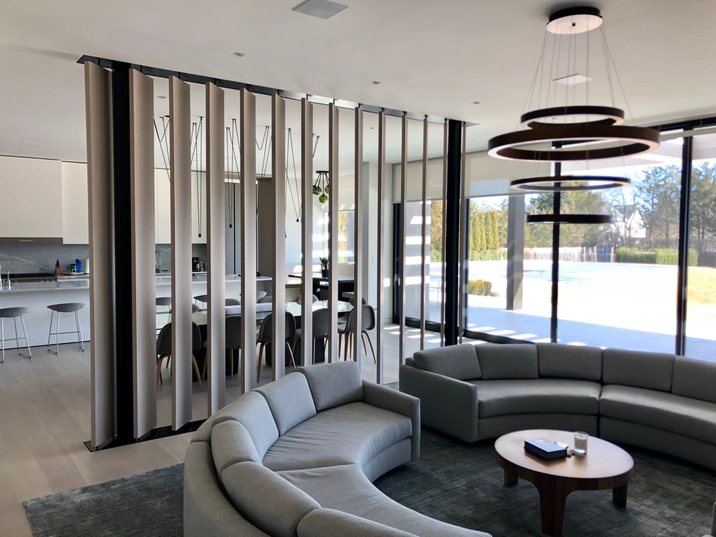 Open-plan living room featuring a floor-to-ceiling vertical timber slat partition separating the dining area