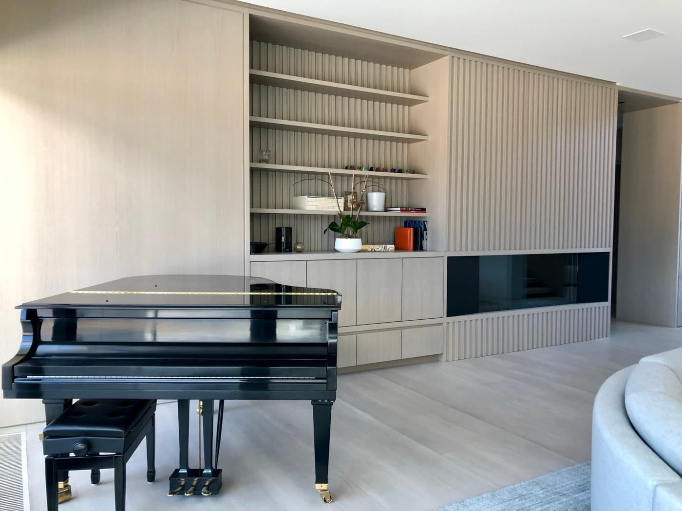 Living room featuring pale timber slatted wall panelling, built-in shelving, and an integrated fireplace