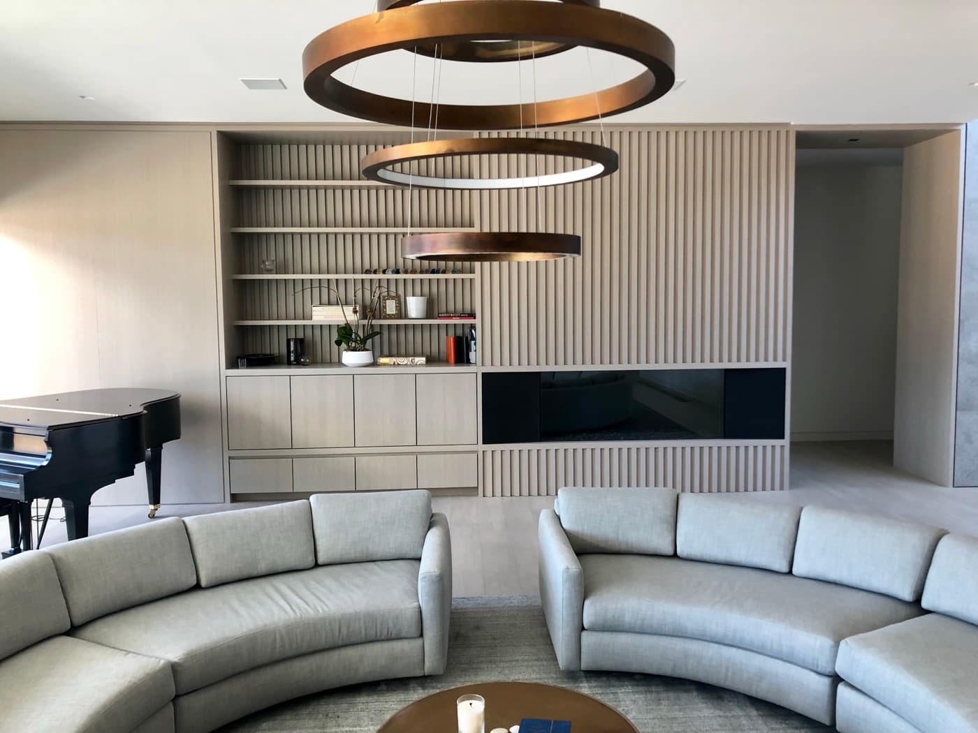 Living room with slatted pale timber panelling, integrated millwork shelving, and recessed fireplace