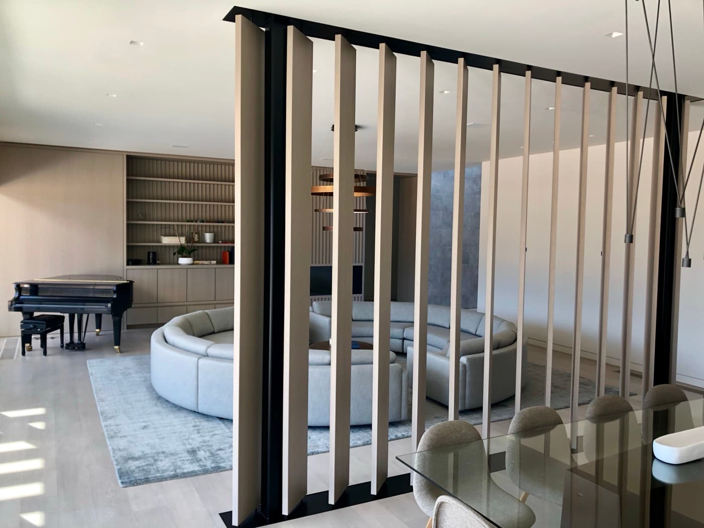 Open-plan living area featuring vertical timber louver partition screen and custom built-in wall cabinetry
