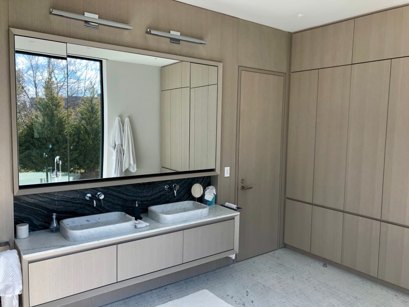 Bathroom featuring full-height timber wall panelling, custom cabinetry, and a floating double vanity