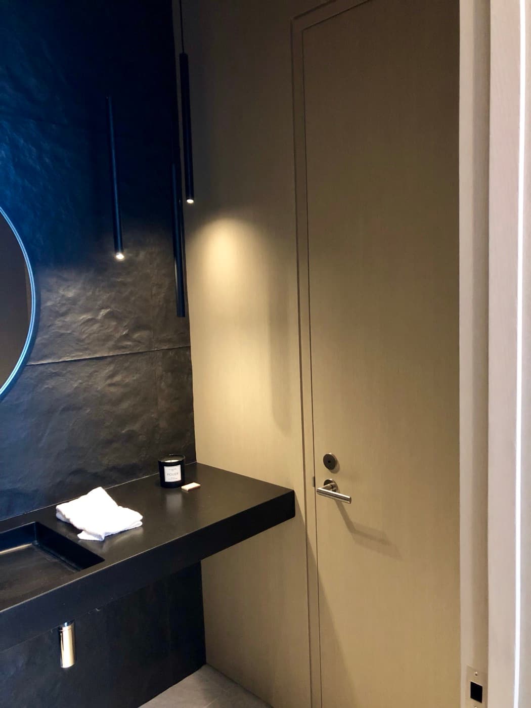 Powder room featuring a floating dark vanity counter, textured dark walls, and seamless flush door