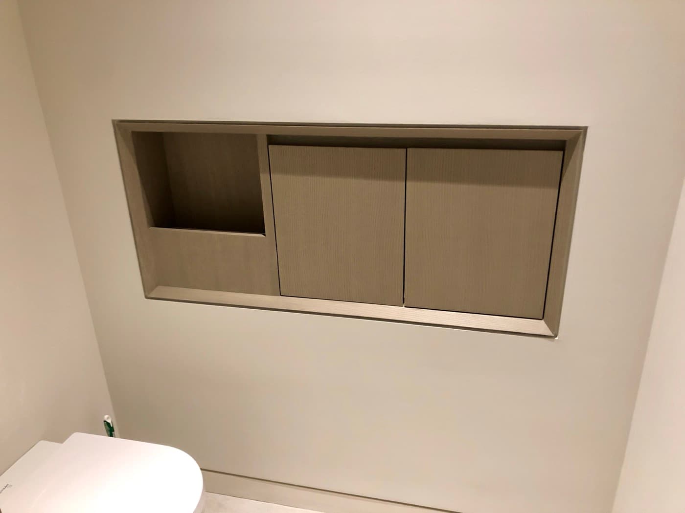 Modern bathroom featuring recessed pale timber storage niche with flush cabinet doors