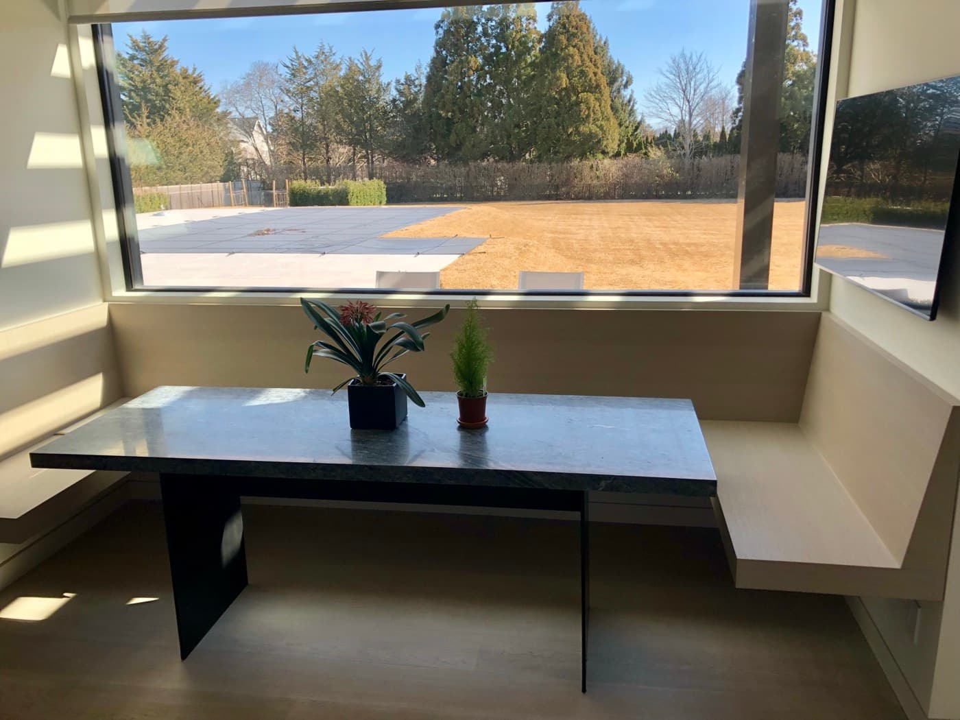Dining nook featuring built-in pale timber banquette seating and a stone-topped dining table