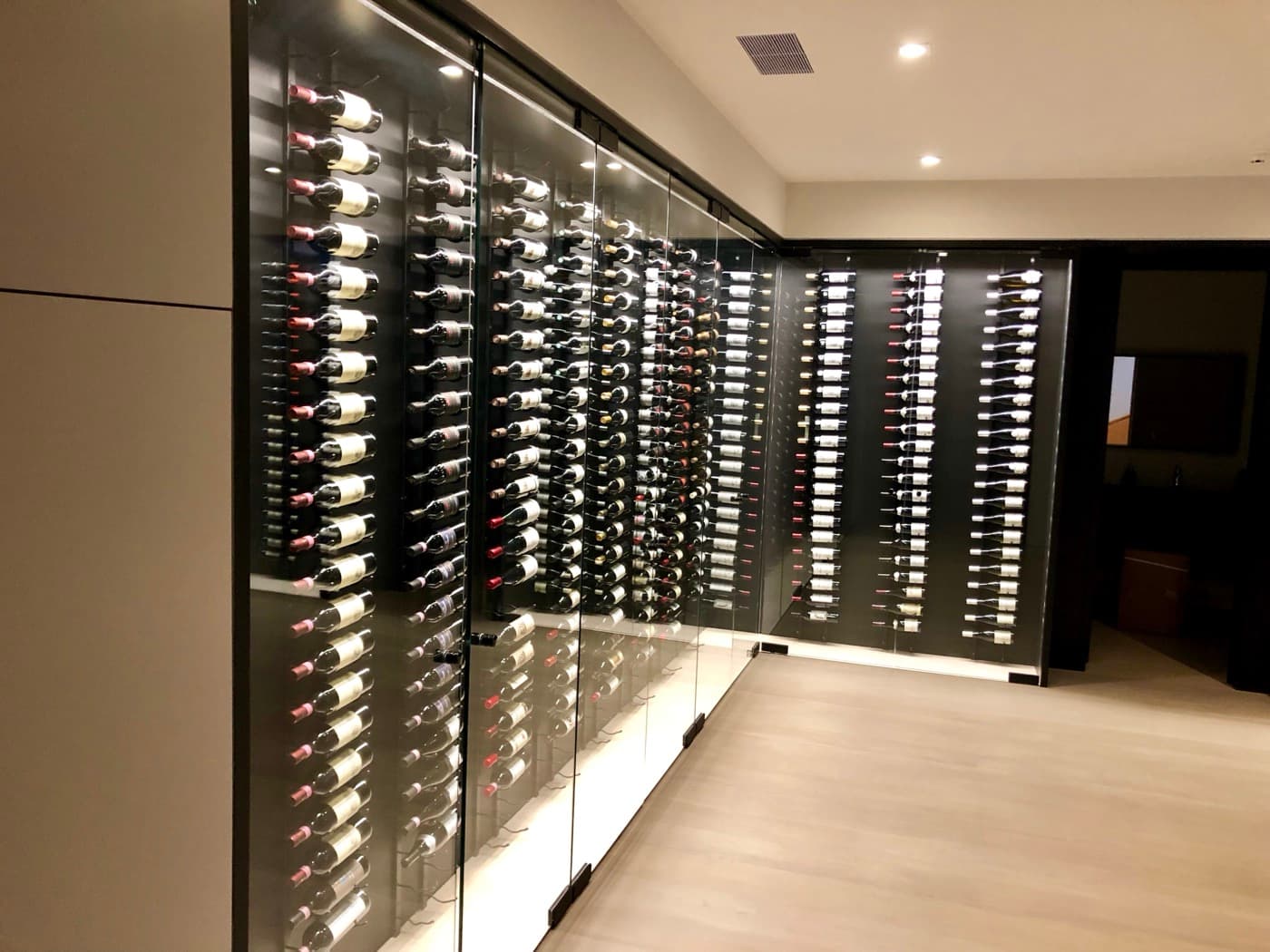 Wine cellar with floor-to-ceiling glass cabinetry, custom bottle racking, and integrated lighting