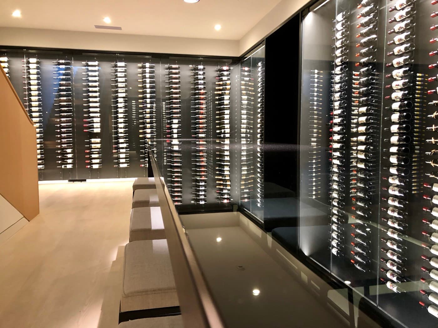 Wine cellar with floor-to-ceiling illuminated glass display cases and built-in tasting counter