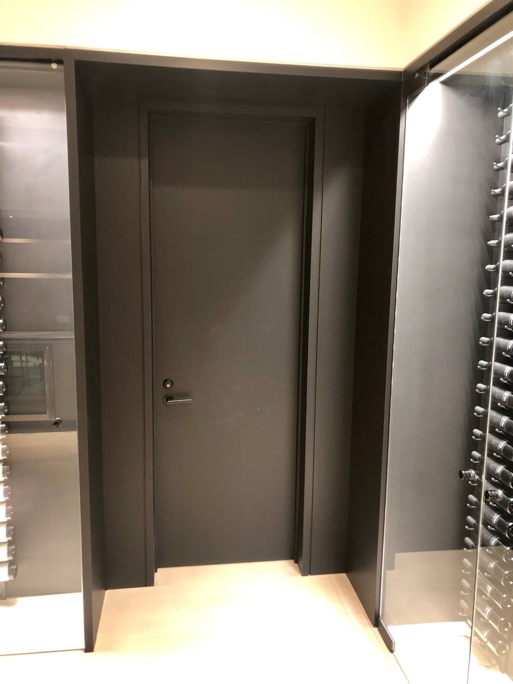 Wine cellar hallway featuring a dark interior door framed by glass-enclosed wine racks