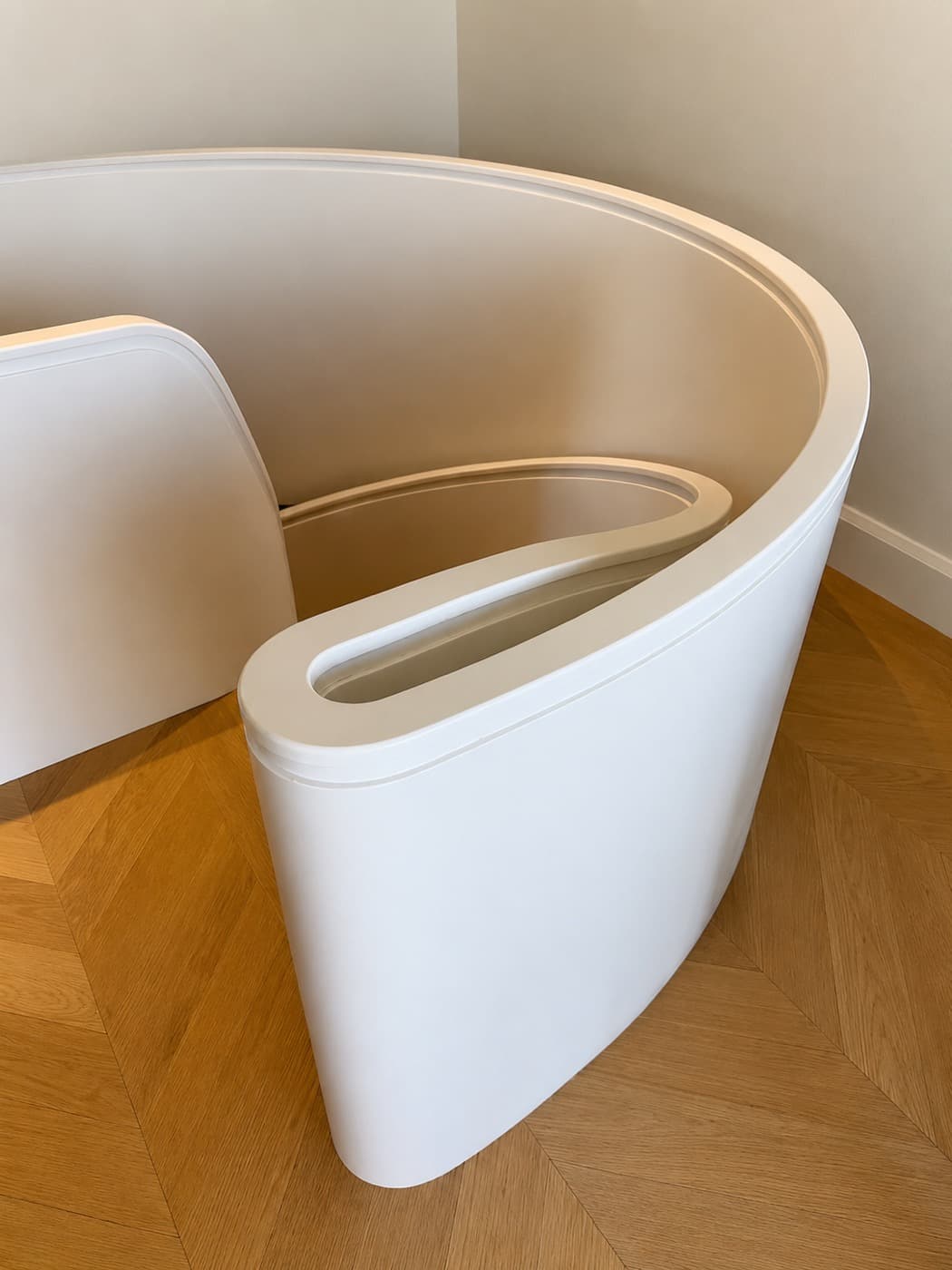 Curved white staircase balustrade rising from a herringbone timber floor in a modern interior