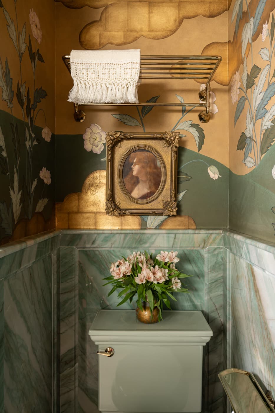 Powder room with green veined stone wainscoting, decorative floral wallpaper, and brass towel rack
