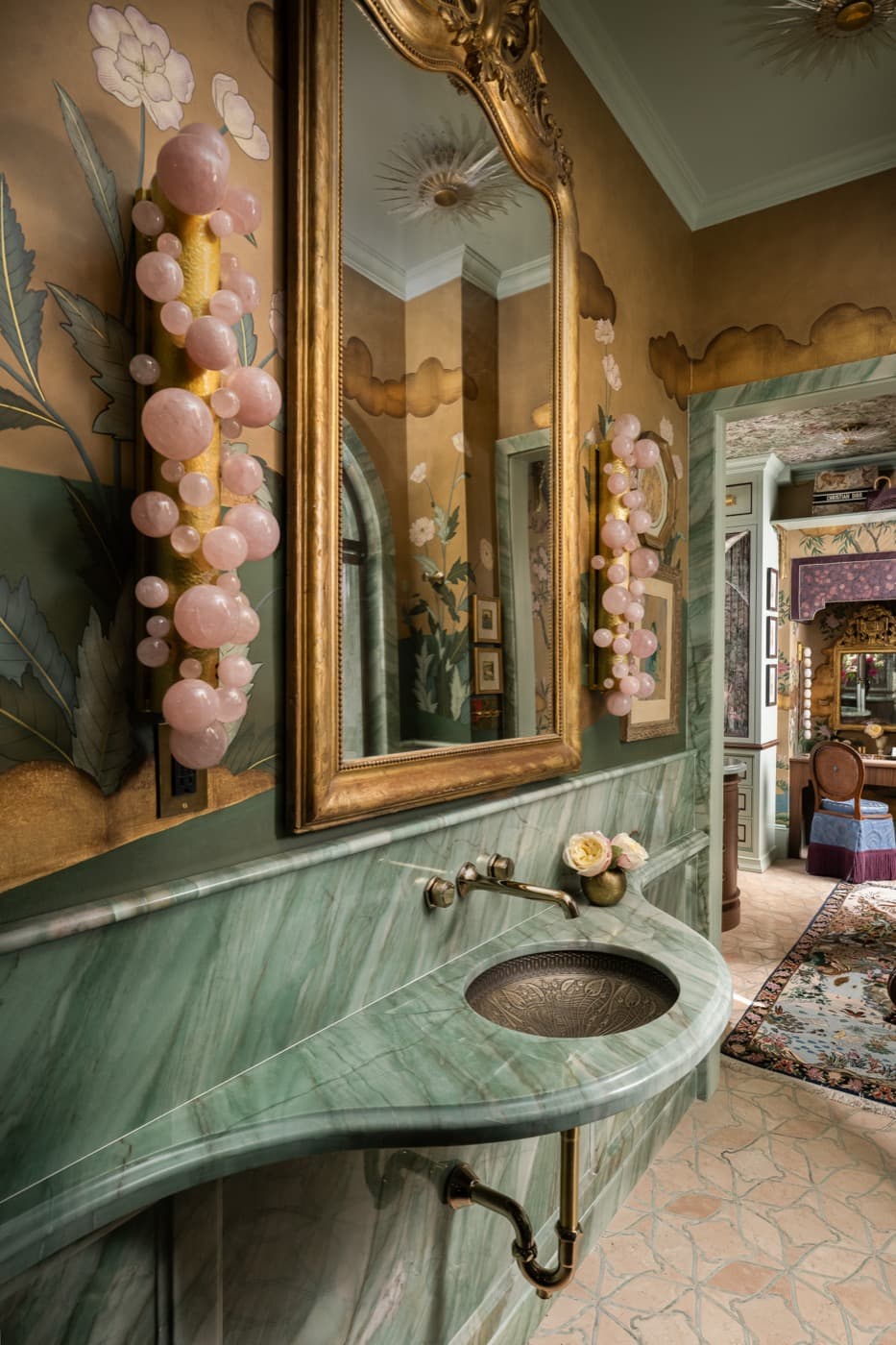 Powder room featuring a curved green veined stone vanity and ornate gilded mirror