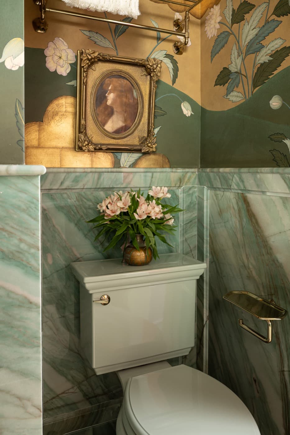 Powder room featuring green veined stone wainscoting, pale toilet, and floral wallpaper