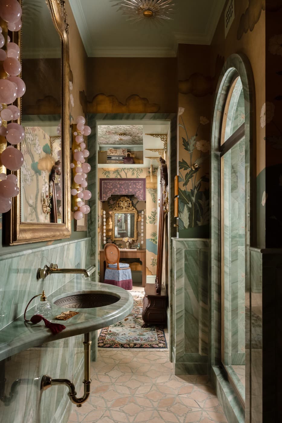 Powder room featuring green veined stone wainscoting, a wall-mounted sink, and arched stone doorway