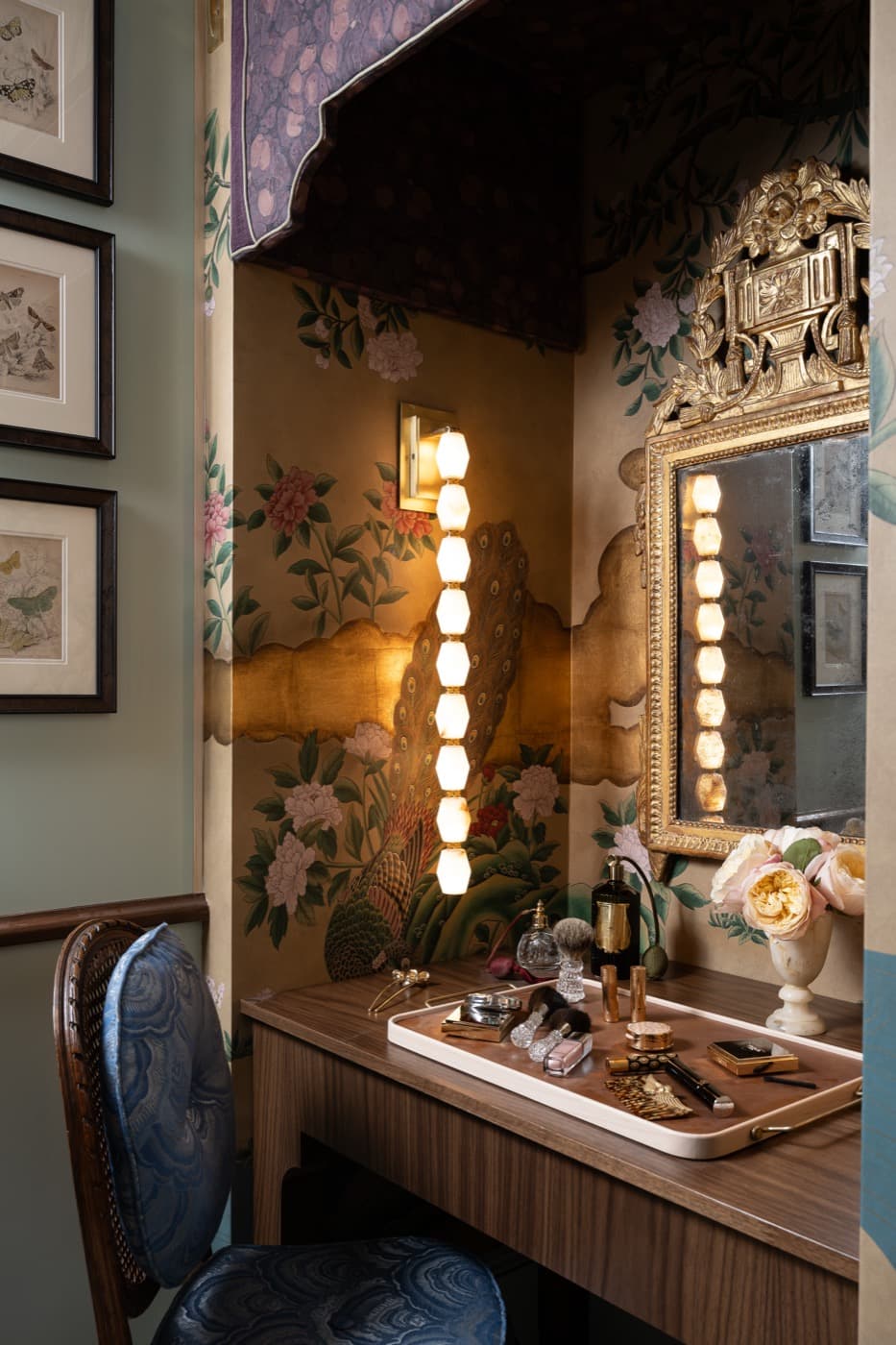 Dressing nook with dark timber vanity desk, vertical wall sconce, and ornate gilded mirror