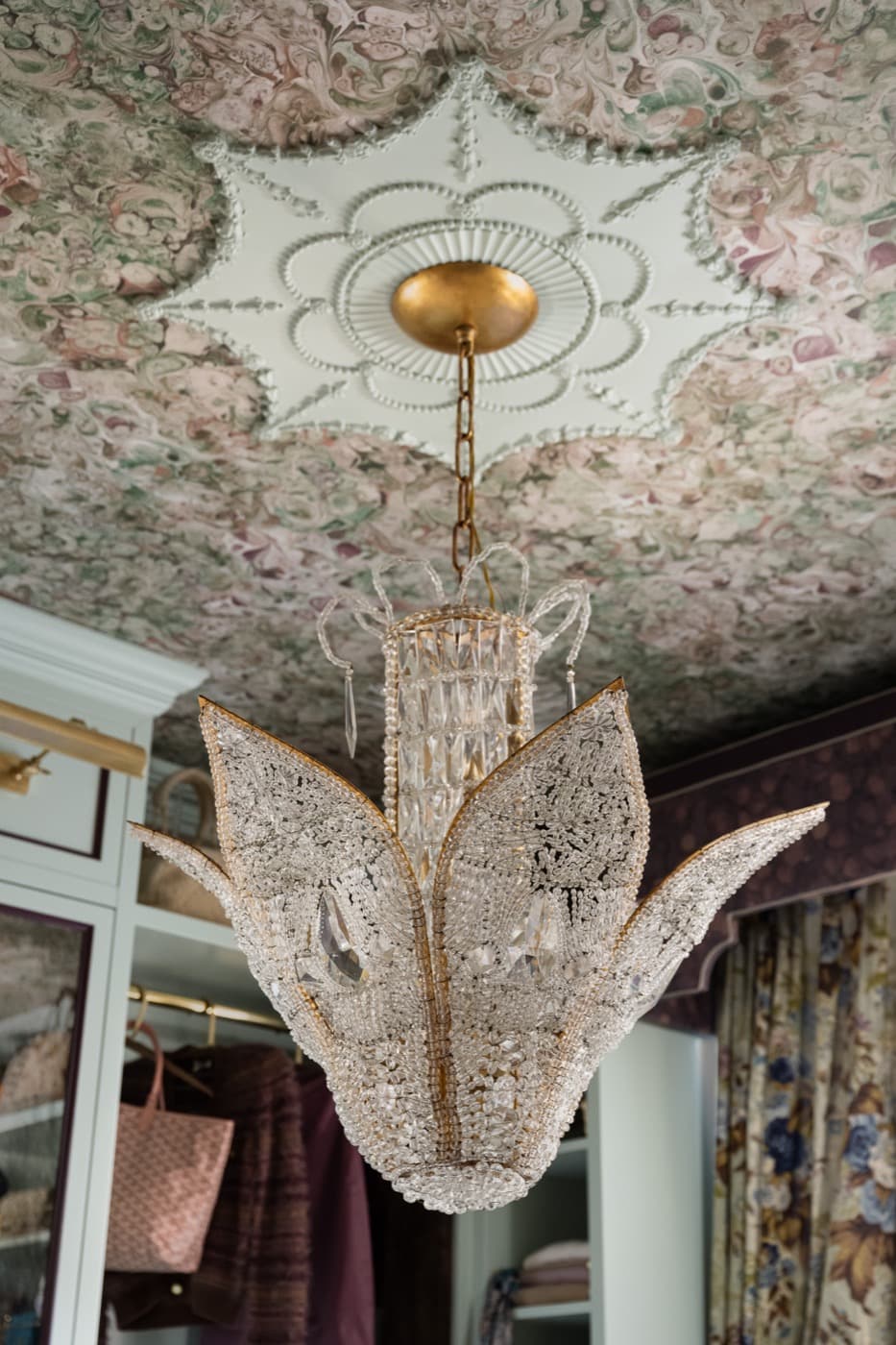 Dressing room featuring an ornate crystal chandelier, decorative ceiling medallion, and custom painted wardrobe millwork