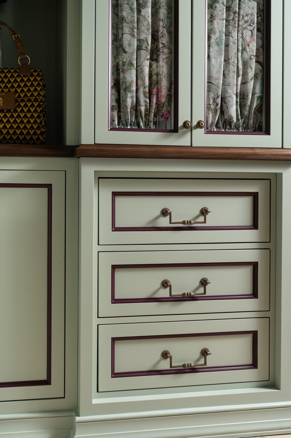 Dressing room built-in cabinetry featuring painted drawers with contrasting trim and brass-toned pulls