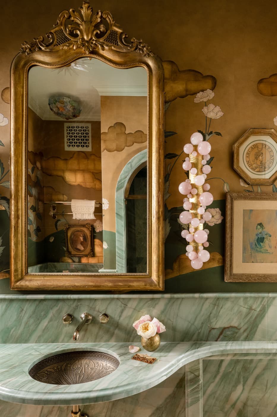 Powder room with curved green veined stone vanity countertop and ornate gilded mirror