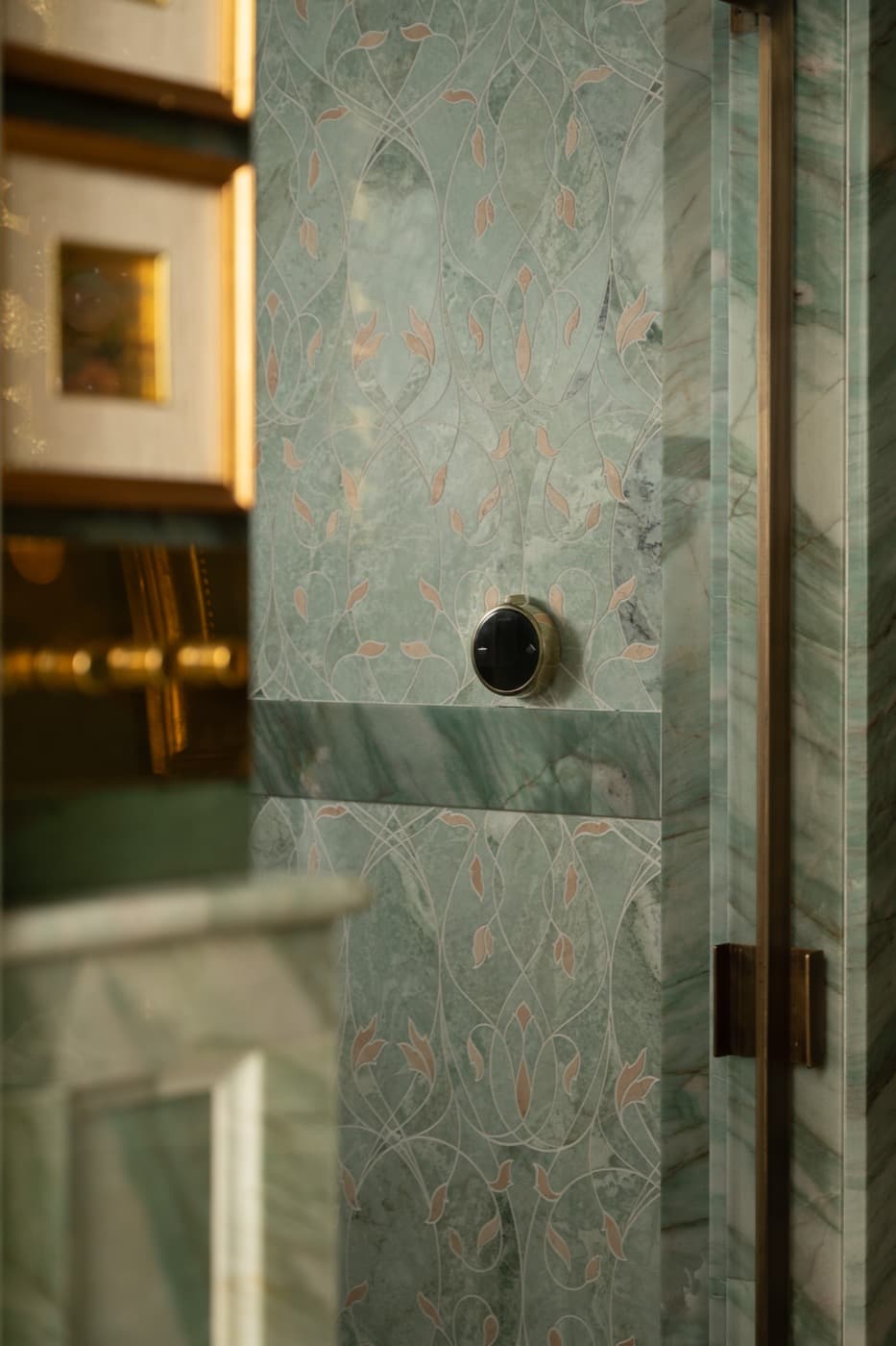 Bathroom detail featuring inlaid green stone wall panelling and bronze-toned metal trim