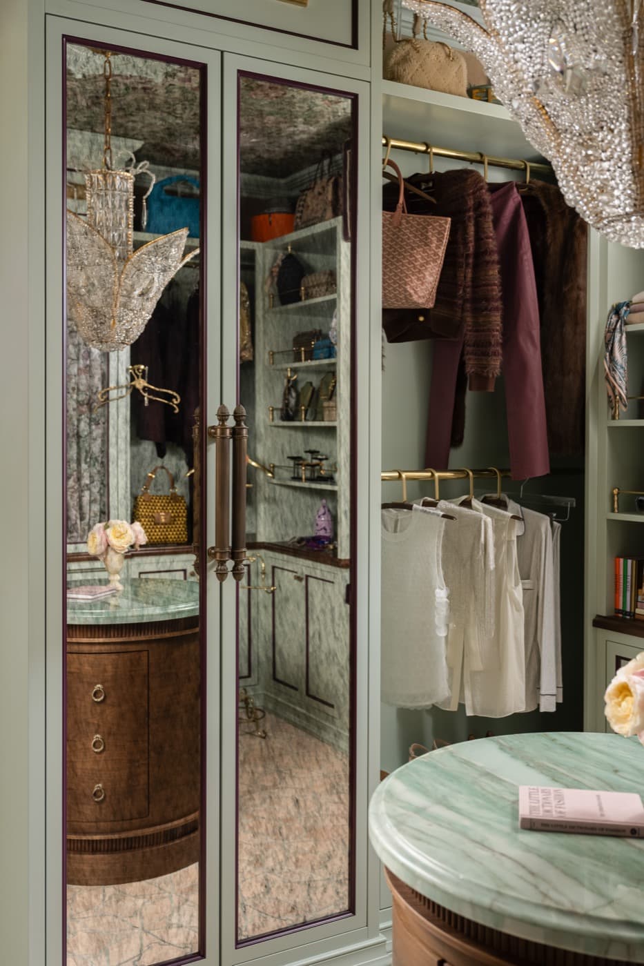 Walk-in closet featuring mirrored wardrobe cabinetry, open hanging storage, and a rounded stone-topped island
