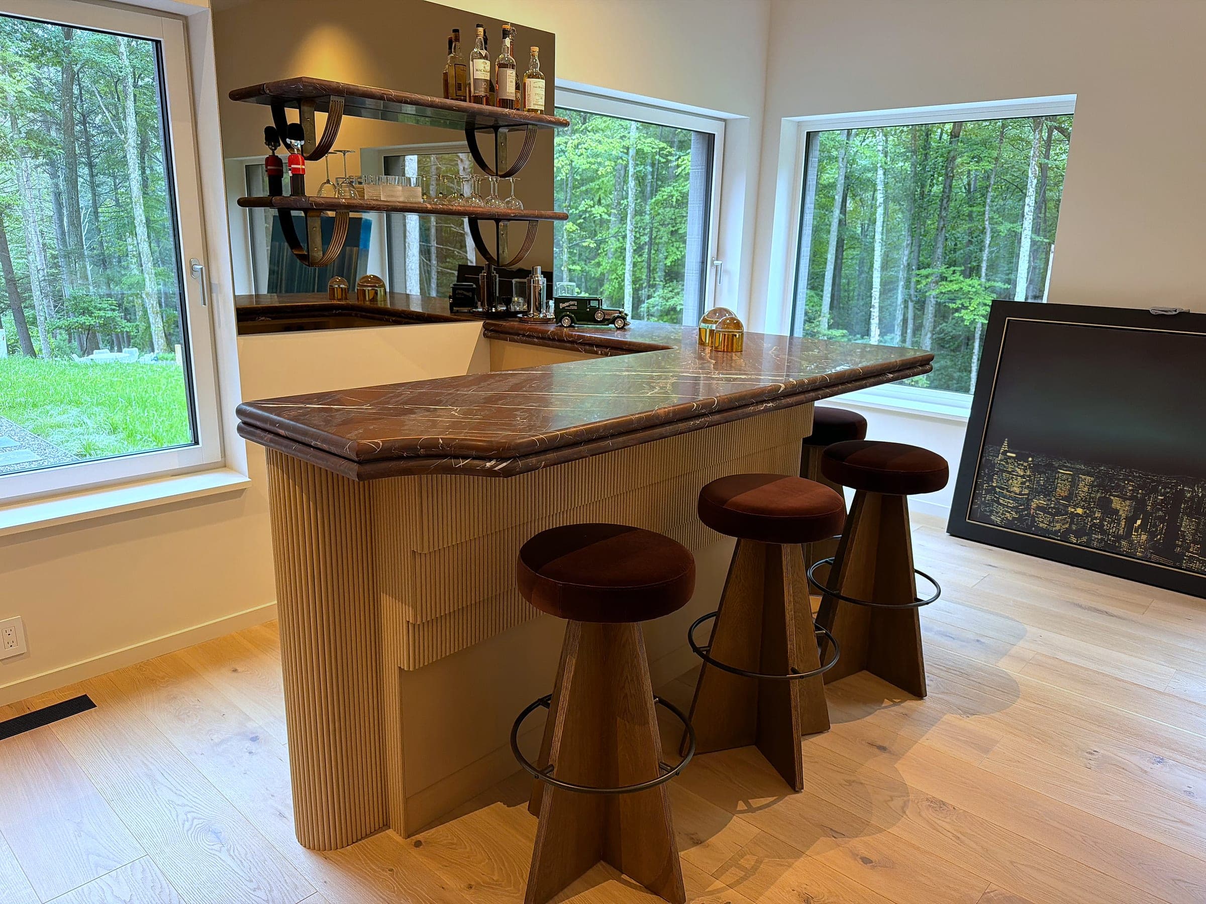The bar from the side, showing the fluted white oak base returning around the corner beneath the stone top