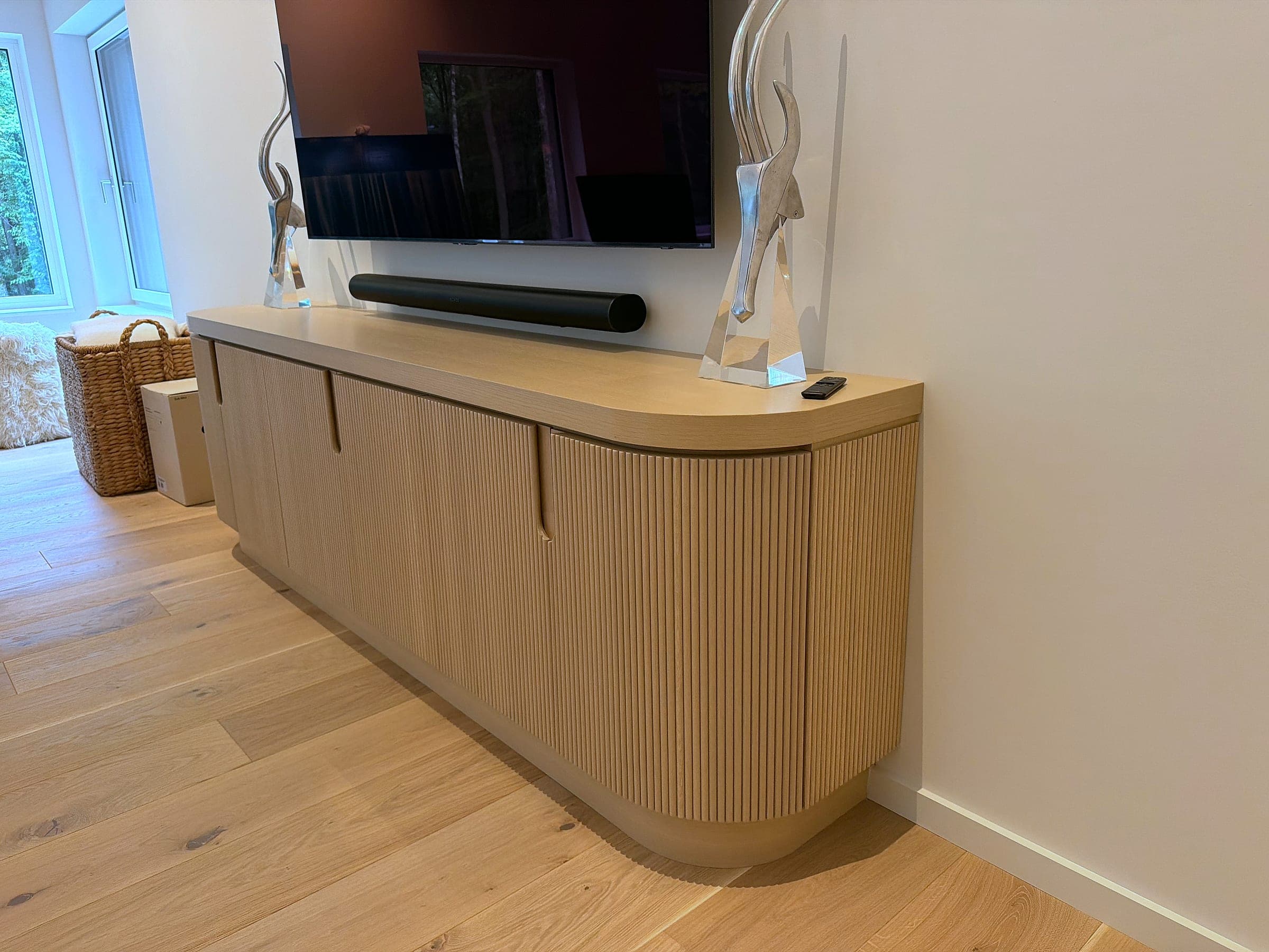 The media credenza from the end, showing its curved return and the length of the fluted front